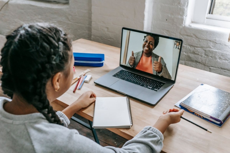 Élève avec un cahier suivant un cours de maths en ligne sur ordinateur portable