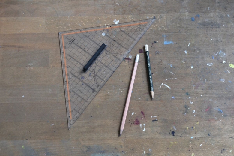 Équerre, règle et crayons posés sur une table pour faire de la géométrie